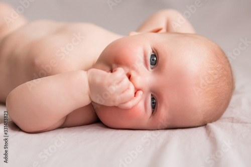 Happy 3 months old baby smiling, lying on white bed