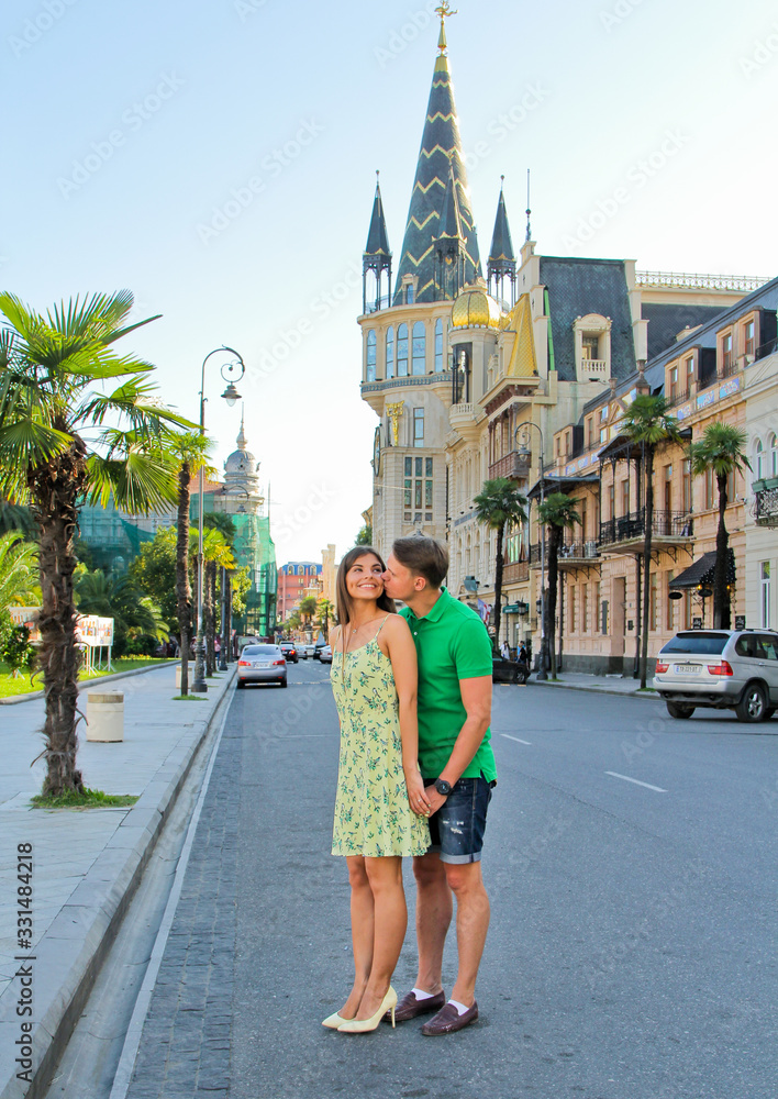 Obraz premium Man kissing and hug his woman. Romantic vacation. Young couple walking outdoors in summer Batumi city, Georgia.