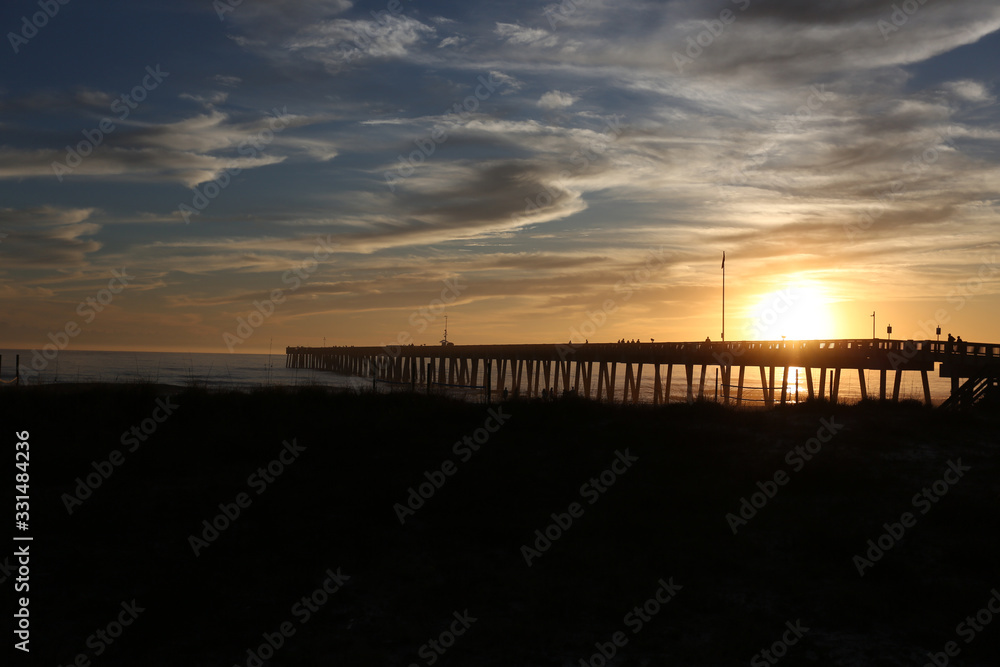 sundown at panama city beach pier with silhouette beach and pier and sunset clouds and sky