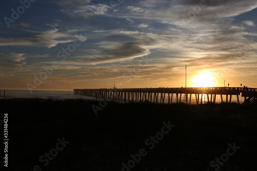 sundown at panama city beach pier with silhouette beach and pier and sunset clouds and sky © lightrapture