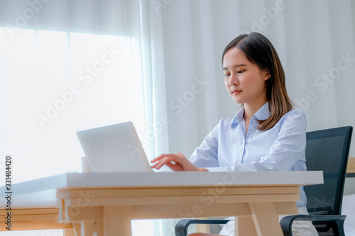 Pretty business Asian girl work at home with laptop in the bedroom with day light.