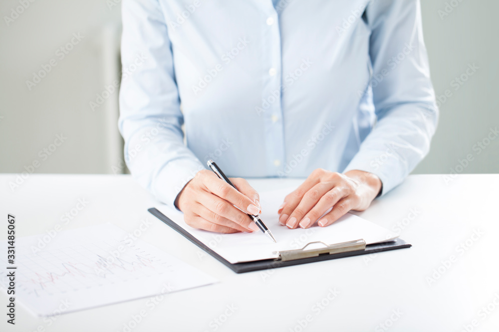 Woman's hands writing on sheet in a clipboard with a pen. Woman's hands writing on sheet in a clipboard with a pen.