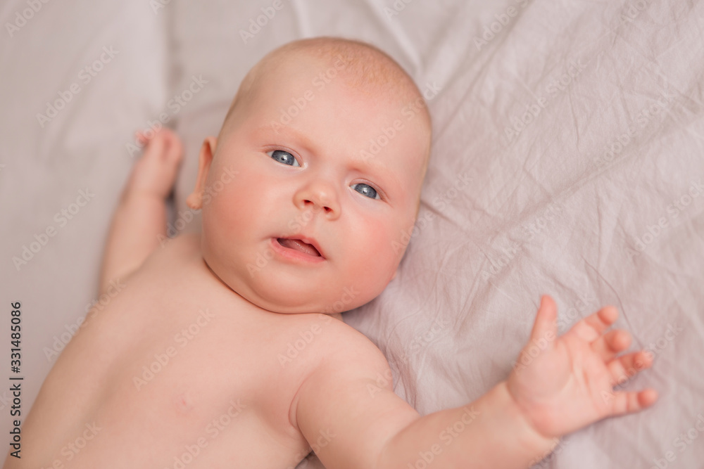 Happy 3 months old baby smiling, lying on white bed Happy 3 months old baby smiling, lying on white bed