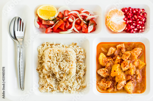 Photos Traditional Turkish Meal with chicken potato,rice,tomato salad and fruits in the white portion food tray