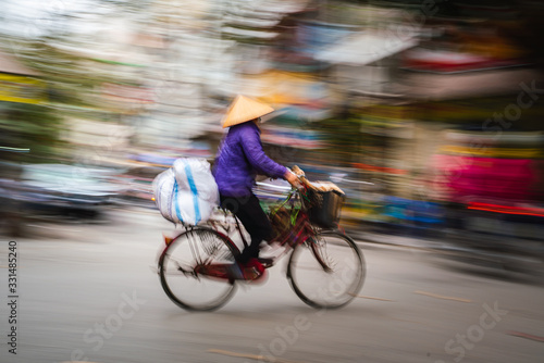 Crowded places Hanoi. Woman on a bike.
