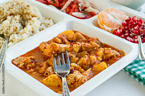 Foto Traditional Turkish Meal with chicken potato,rice,tomato salad and fruits in the white portion food tray
