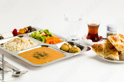Ramadan iftar meal with soup rice with chicken chickpea vegetable salad dessert and dry fruits in the stainless steel portion food tray.Top view fulled frame.