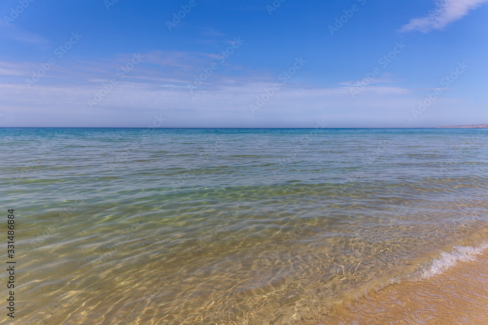 Obraz premium View of blue sea waves at sandy beach. Horizon line. Caspian Sea, sandstone coast. ustyurt. Selective focus, long shutter speed