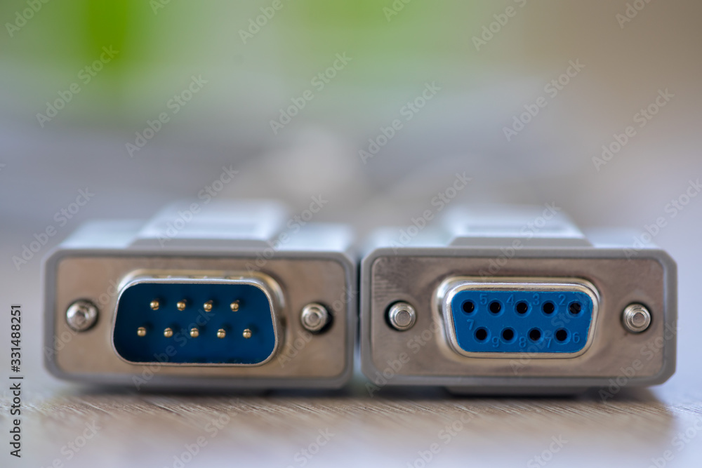 Close-up of a RS-232 serial port. Male to female extension cord on a wooden table.