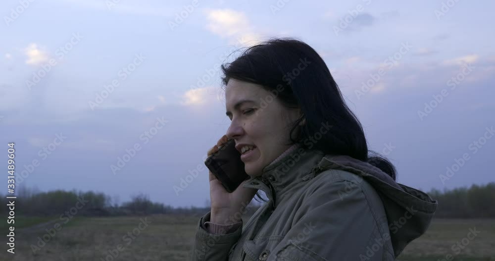 Young Woman Talking On Phone While Standing in The Field. Hiking, Walking, Running in the Morning, Evening. Winter - Spring Countryside Rural Scenery Landscape. Young Woman Talking On Phone While Standing in The Field. Hiking, Walking, Running in the Morning, Evening. Winter - Spring Countryside Rural Scenery Landscape.