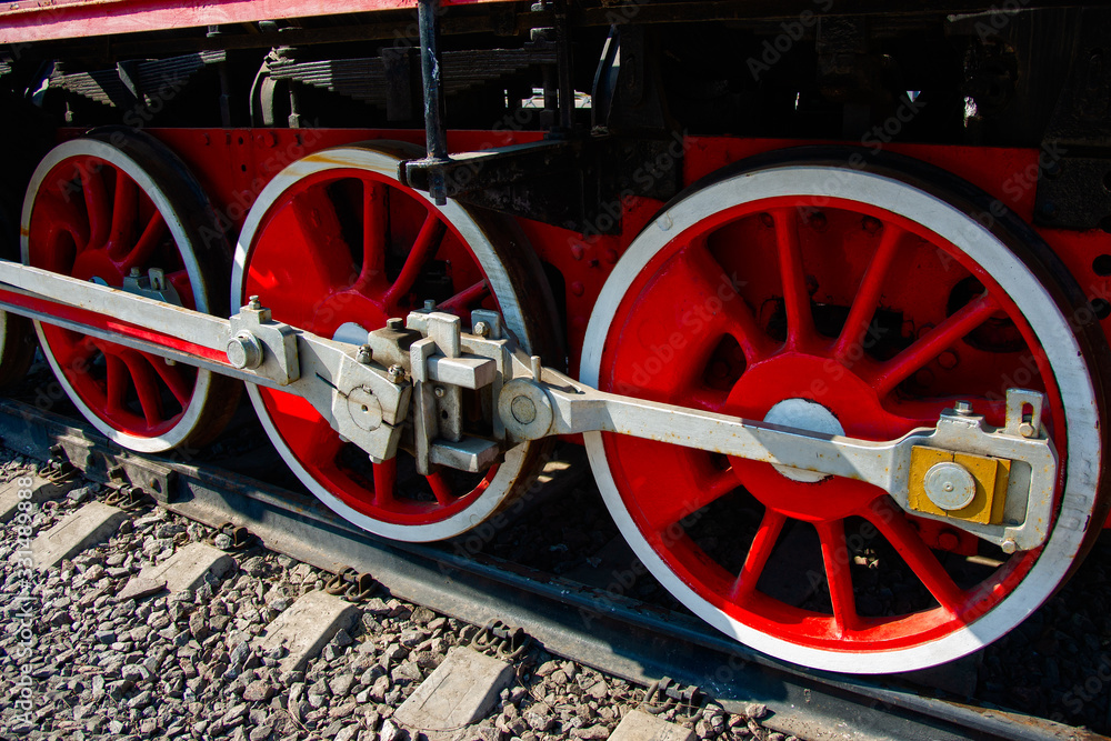 Red driving wheels of a vintage steam engine locomotive. Driving rods, drives, cranks and other parts. The history of railway transport.