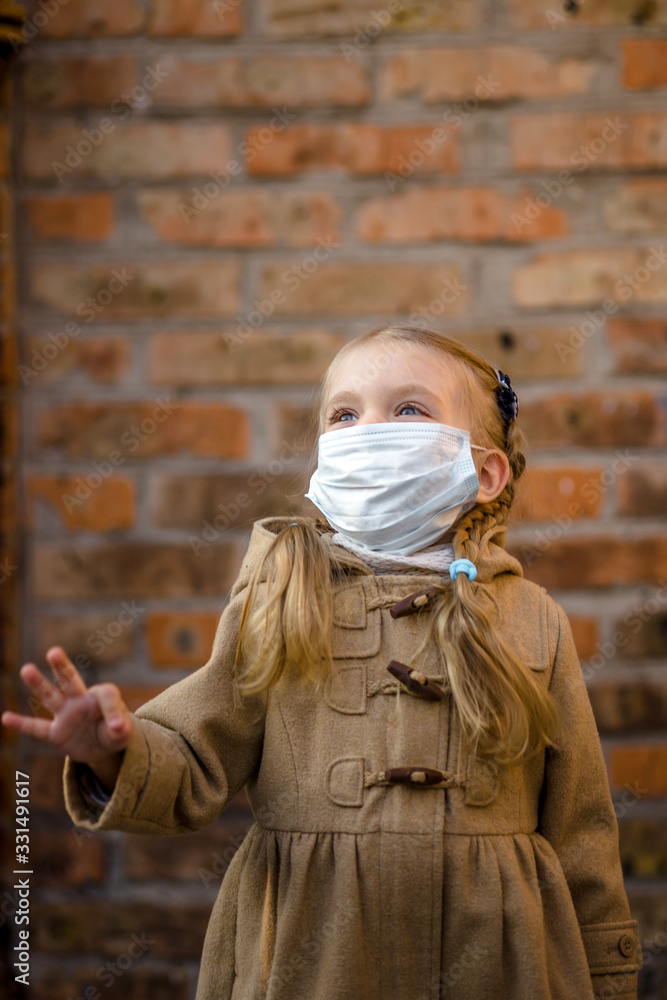 little girl in a mask from coronavirus. the fight against the virus. Against the background of a brick wall. little girl in a mask from coronavirus. the fight against the virus. Against the background of a brick wall.