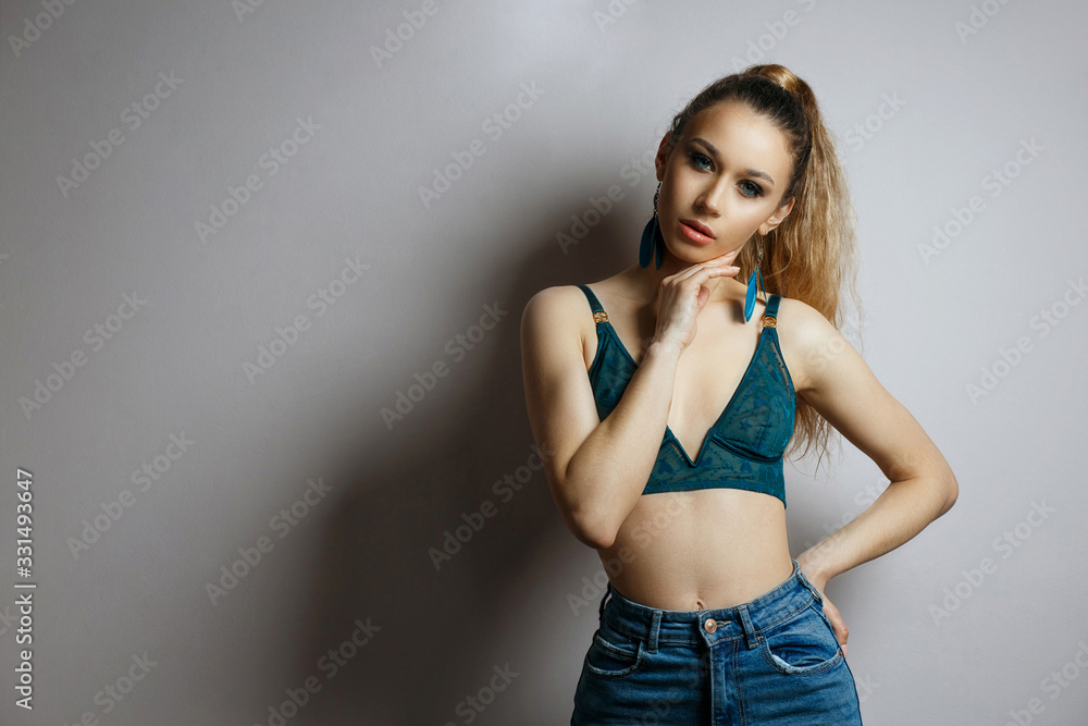 Sexy blonde girl wears green bra and blue jeans