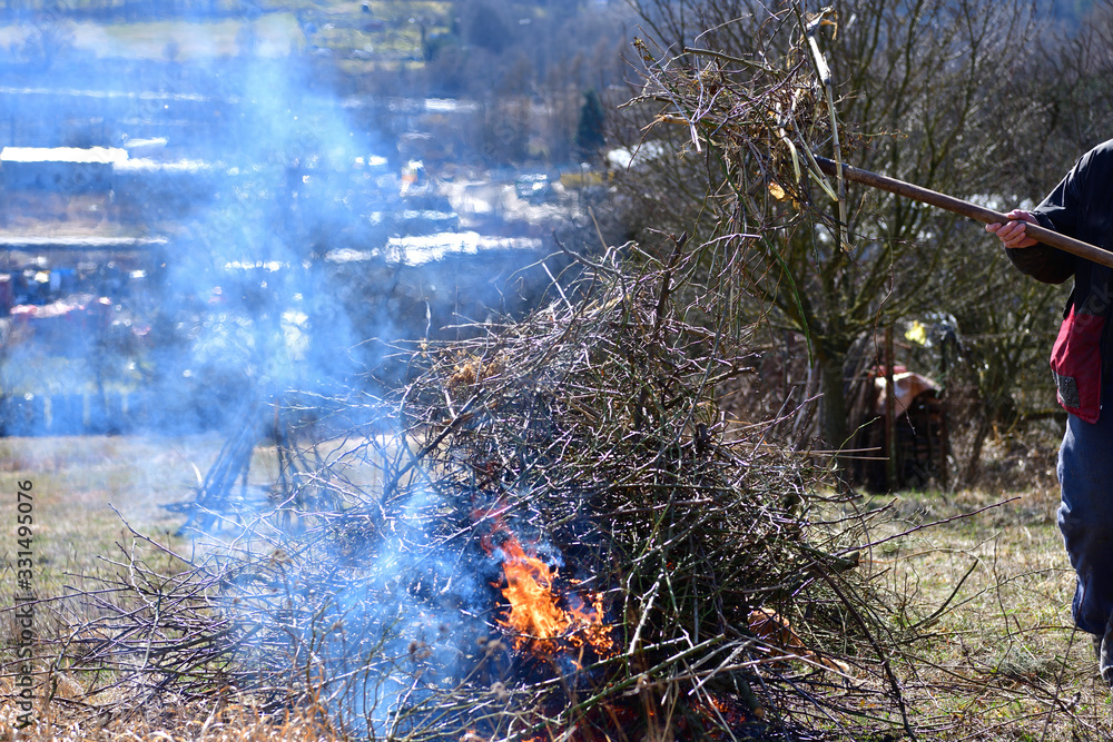 Farmer burns old leaves and branches in the spring Farmer burns old leaves and branches in the spring