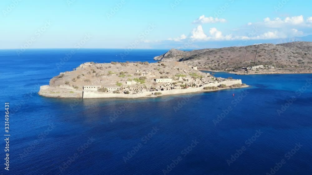 Spinalonga and Spinalonga peninsula, aerial shot, camera fly back, away from famous island. Calm sea waters surround former fortifications on small isle at Lasithi, North-East Crete Island Spinalonga and Spinalonga peninsula, aerial shot, camera fly back, away from famous island. Calm sea waters surround former fortifications on small isle at Lasithi, North-East Crete Island