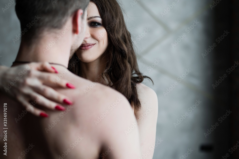 Naklejka premium Female hands on the bare back of an unrecognizable man. A young couple cuddles in the bedroom. Love and relationship.