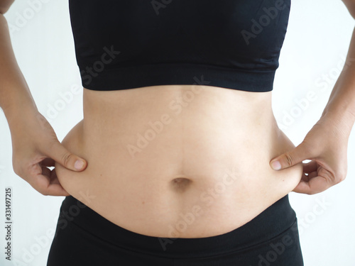 cellulite and belly fat in woman and she grabbing her waist around hip cause of fatty from weight and loss of collagen use for body firming gel or cream product or liposuction concept