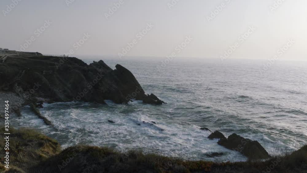 Beautiful beach near a lighthouse, surrounded by rocks and cliffs Beautiful beach near a lighthouse, surrounded by rocks and cliffs