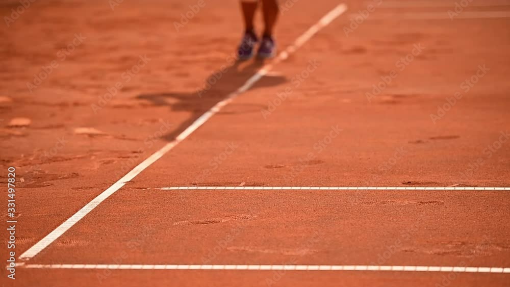Tennis player and his shadow are seen on a clay court during a competition Tennis player and his shadow are seen on a clay court during a competition