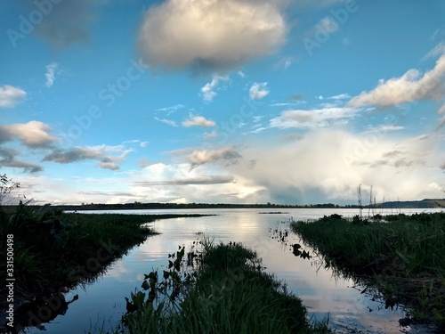 transport tracks on the grass filled with water from the river on the background of a beautiful evening sky with unusual clouds