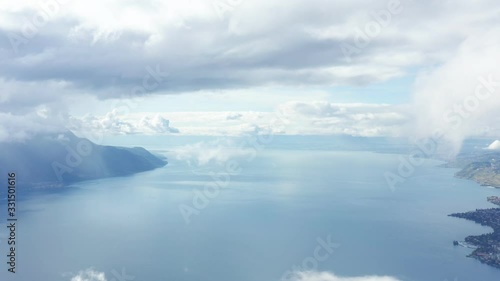 AERIAL: Flight forward through fir trees at mountain to Lake Geneva. Perspective shot good for titles