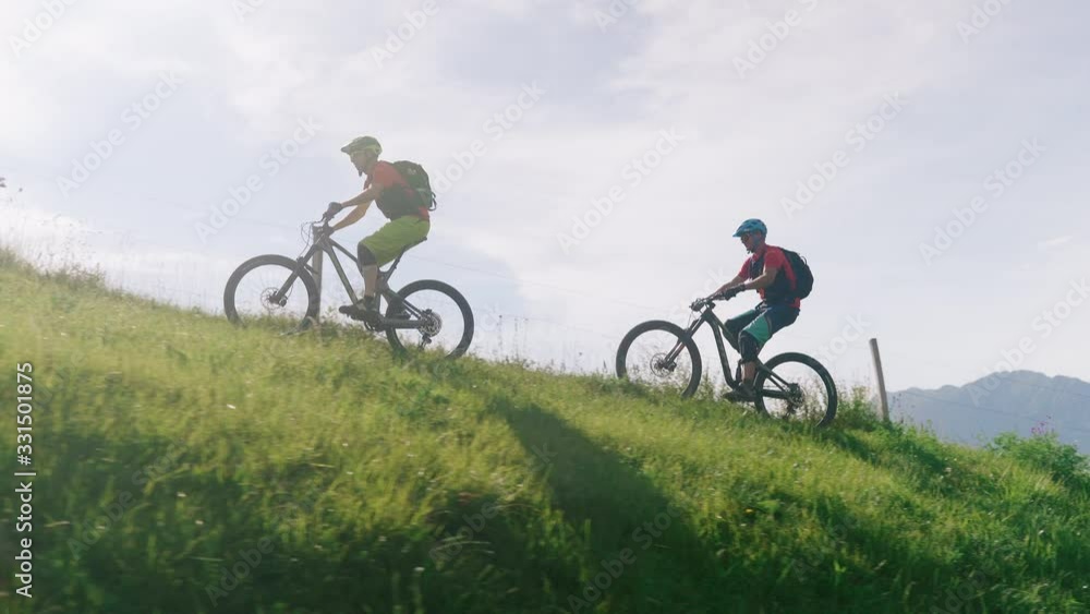 Two men biking riding uphill on a mountain bike trough the forest trails slow motion Two men biking riding uphill on a mountain bike trough the forest trails slow motion