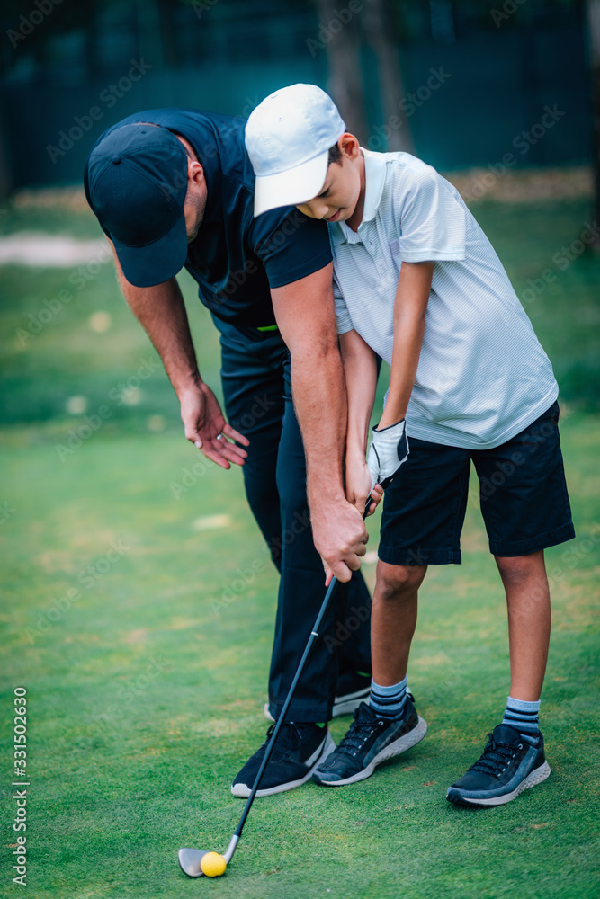 Obraz premium Golf – Personal Training. Golf Instructor Teaching Young Boy How to Play Golf.