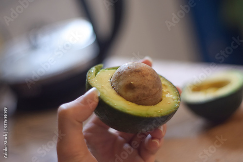Avocado in hand on the background of the kitchen