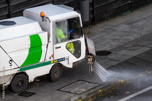 Street cleaning machine working in city. Sweeper cleaning the sidewalk with pressurized water. Maintenance or cleaning concept