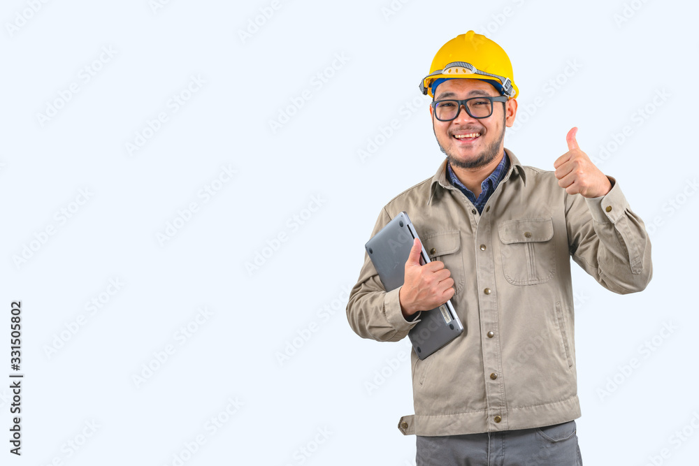 Young computer engineer asian man with laptop and yellow hard hat , Asian man point on empty space Young computer engineer asian man with laptop and yellow hard hat , Asian man point on empty space