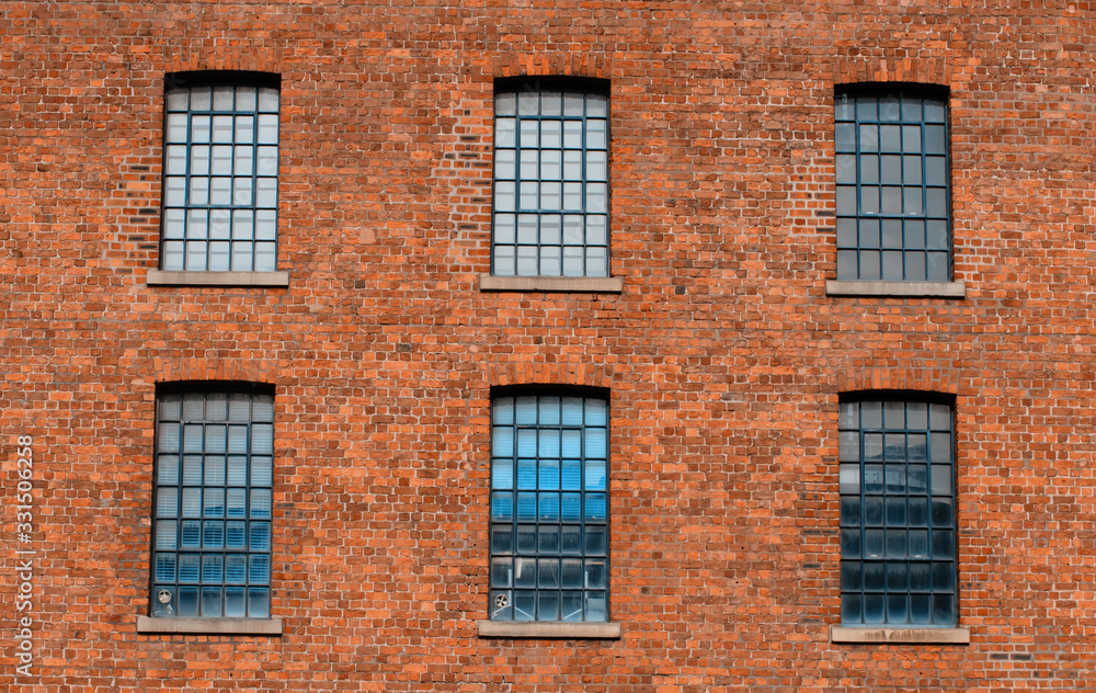 Facade / front  of an old factory building made of red brick with a lot of vintage windows