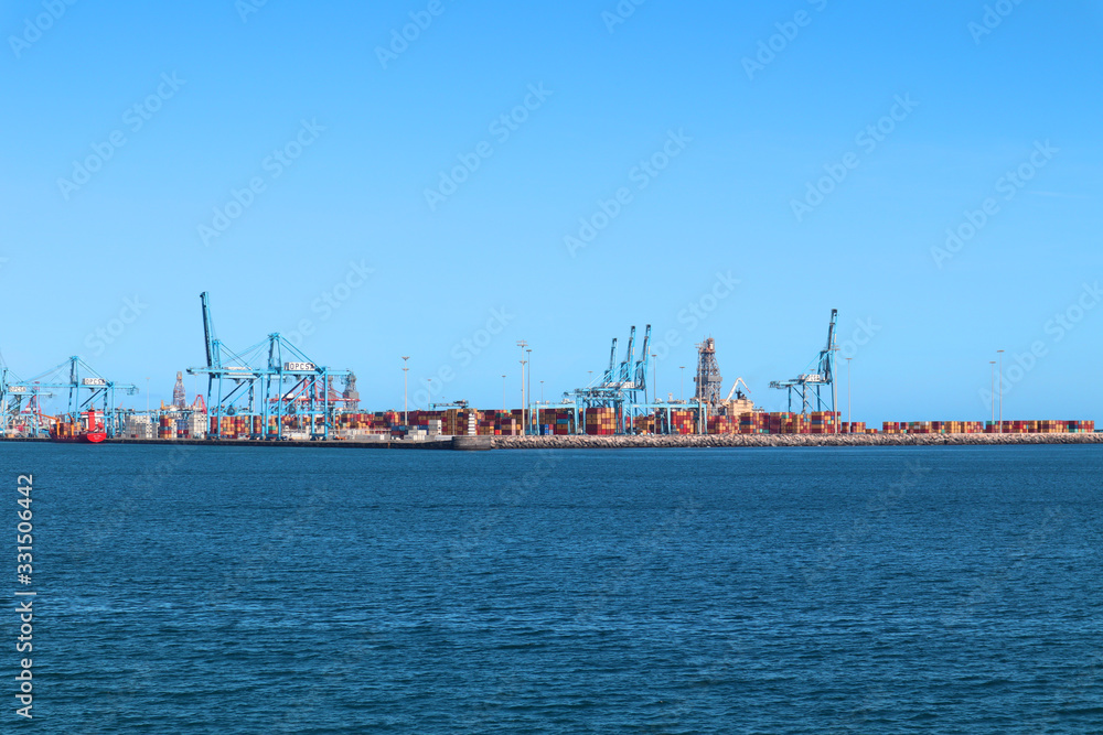 Commercial harbour with cranes, container for imports and exports in a beautiful day