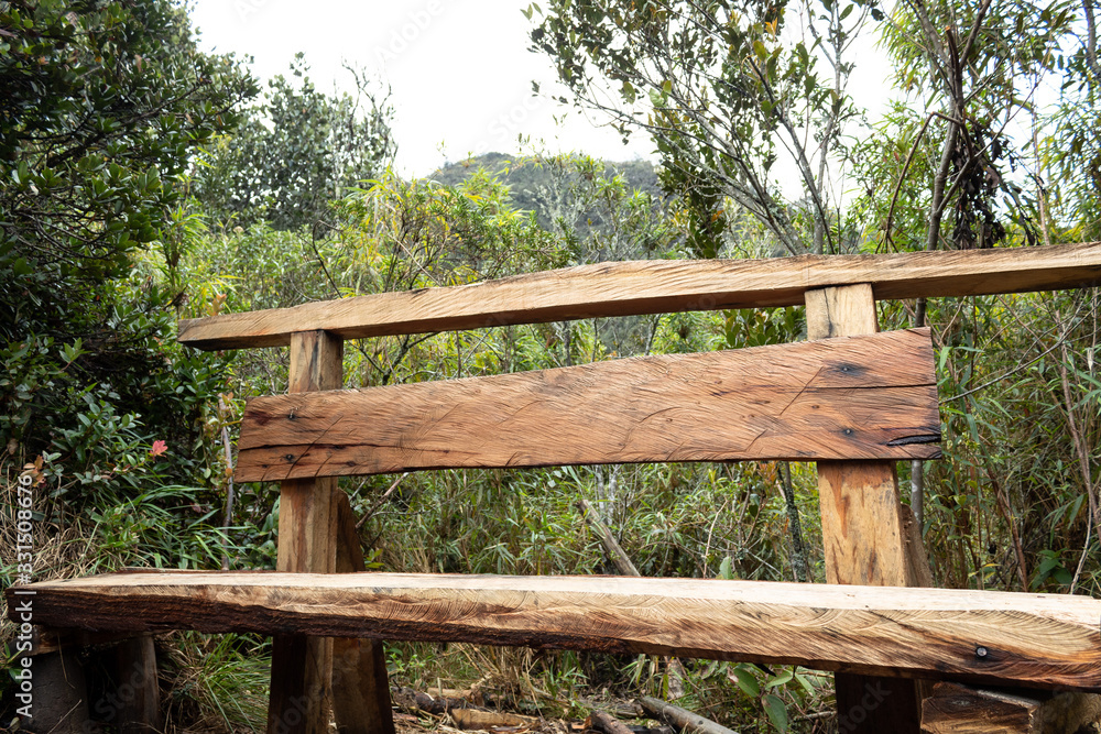 artesanal Wooden bench bank in middle of trekking path at andes mountain near to bogota city with nature and mountains at background in sunny day artesanal Wooden bench bank in middle of trekking path at andes mountain near to bogota city with nature and mountains at background in sunny day