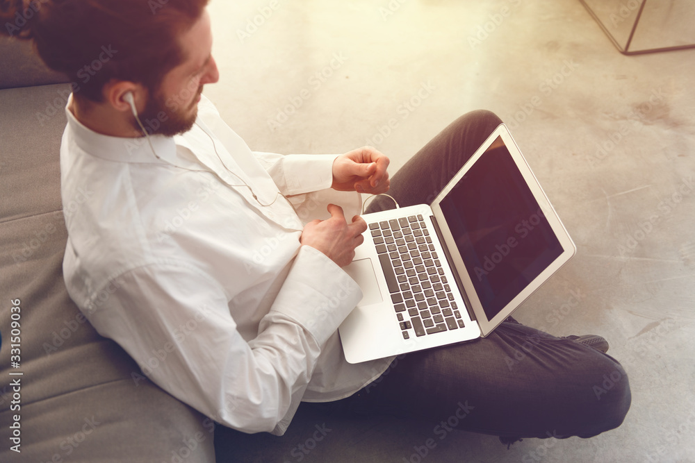 Young businessman sitting on the floor while working from home with a laptop Young businessman sitting on the floor while working from home with a laptop