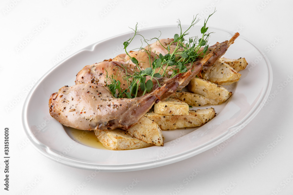 Baked tender juicy rabbit legs with celery. Banquet festive dishes. Gourmet restaurant menu. White background.