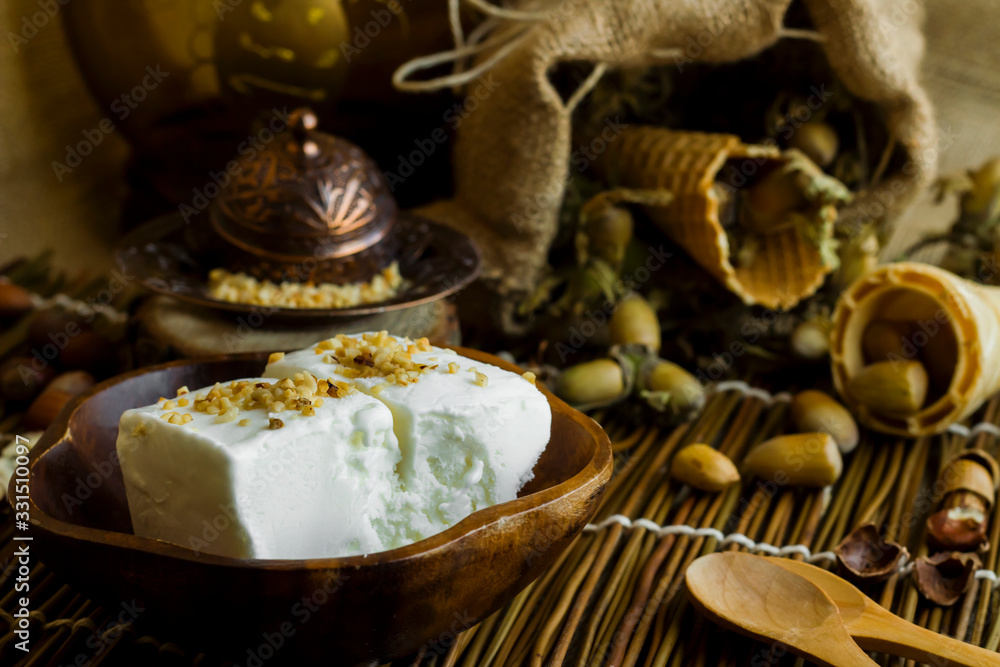 Fototapeta premium Vegan vanilla ice cream made with hazelnut milk in a bamboo cup, freshly minced hazelnuts