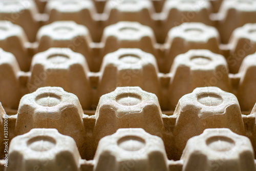 A lot of empty cardboard egg cartons in a row. Bottom of egg trays.