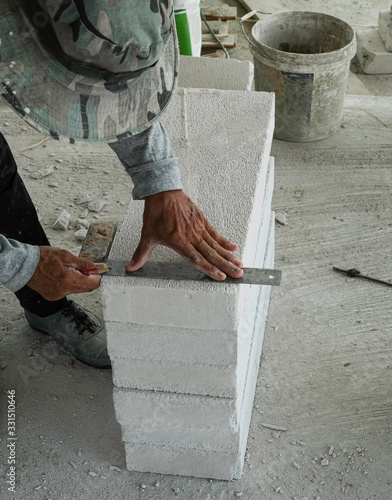 builder worker use stainless steel ruler measure lightweight cement brick prepare for cut to install wall