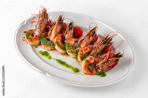 Luxurious seafood salad with grilled king prawns and baked cherry tomatoes. Banquet festive dishes. Gourmet restaurant menu. White background.