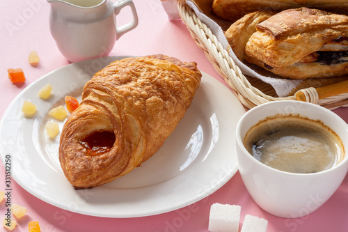 A variety of puff pastry buns with cherries, kiwi, apricot. Rolls, croissants with various fillings. A Cup of coffee with milk, Breakfast. Still-life.