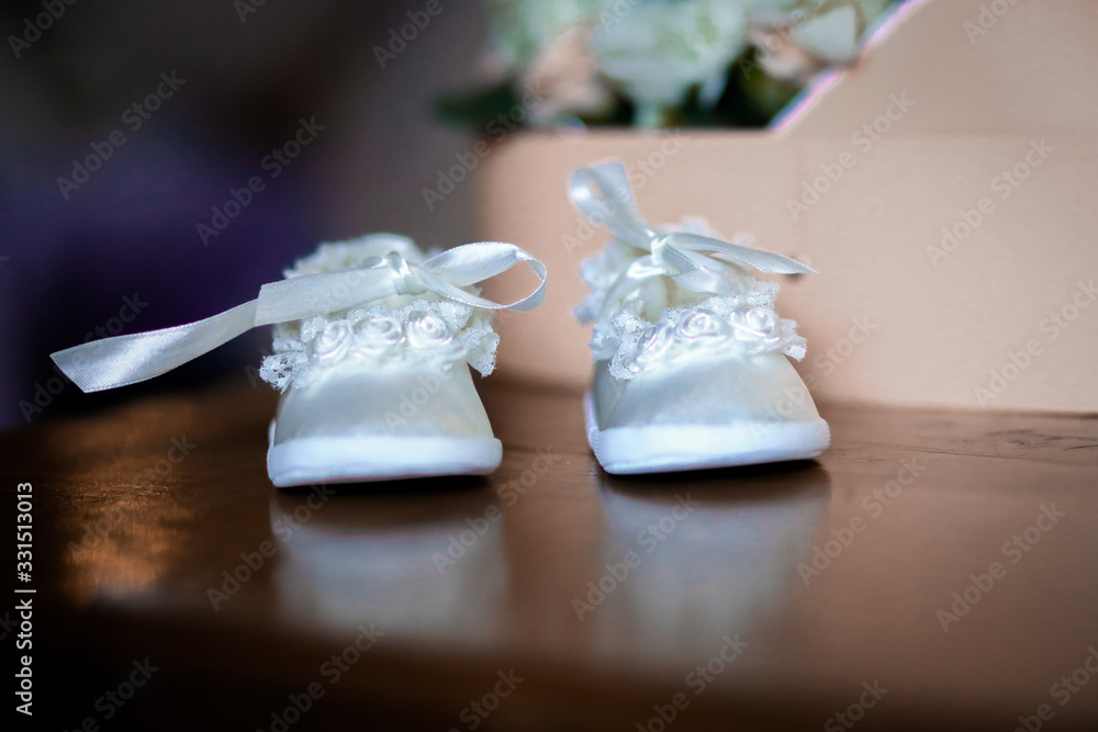 Obraz na płótnie białe buciki na chrzest dla dziewczynki  w salonie