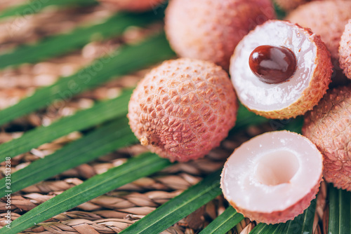 Lychee fruits with palm leaves on rattan background. Copy space. Exotic litchi, lichee fruits. Tropical food concept. photo