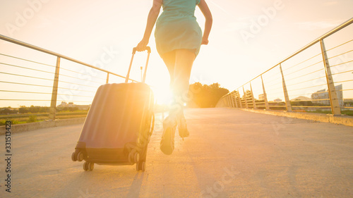 LOW ANGLE: Young woman in heels runs with her luggage to reach airport on time.