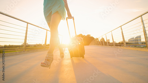 LOW ANGLE: Young woman rushes to the airport with suitcase to catch her flight.