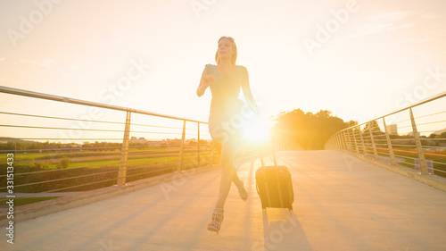 LENS FLARE: Gorgeous woman runs across an overpass to catch her evening flight.