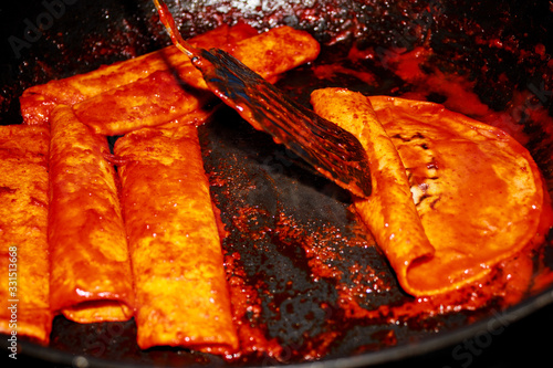 Enchiladas, platillo típico mexicano. Hecho con chiles guajillos y tortillas. Acompañado de cebolla, crema, queso, zanahorias, ppapas y lechuga photo