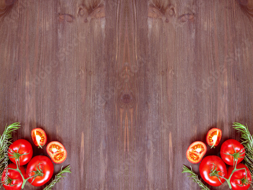 Ripe organic tomatoes and rosemary on a wooden background. Top view with space for writing