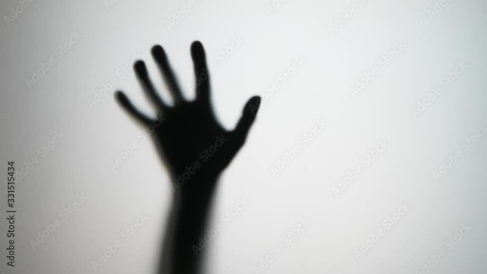 Male hand move from blur and hit glass, horror style shot. Someone wants to go through thick glass wall, flap and smash arm on hard barrier. Black silhouette with white background Male hand move from blur and hit glass, horror style shot. Someone wants to go through thick glass wall, flap and smash arm on hard barrier. Black silhouette with white background
