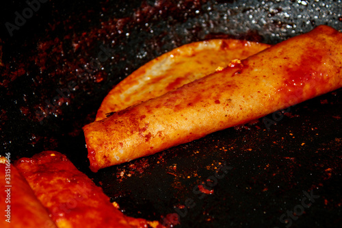 Enchiladas, platillo típico mexicano. Hecho con chiles guajillos y tortillas. Acompañado de cebolla, crema, queso, zanahorias, ppapas y lechuga photo