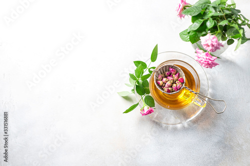 Pink tea buds, a glass cup and vintage strainer.